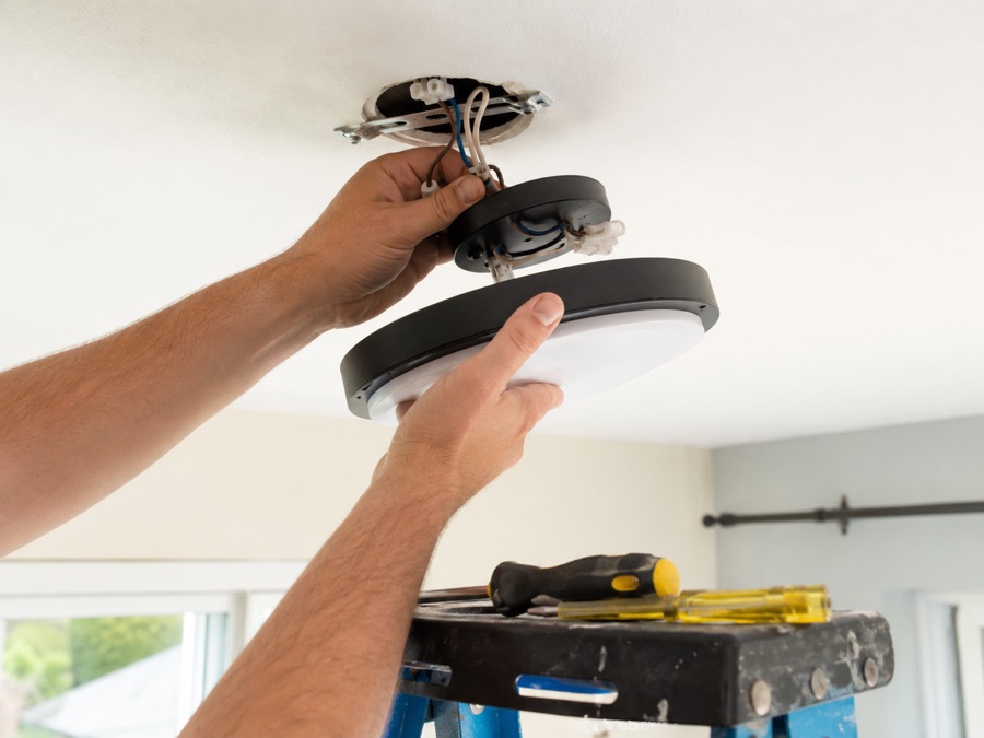 Electrician installing a ceiling light fixture