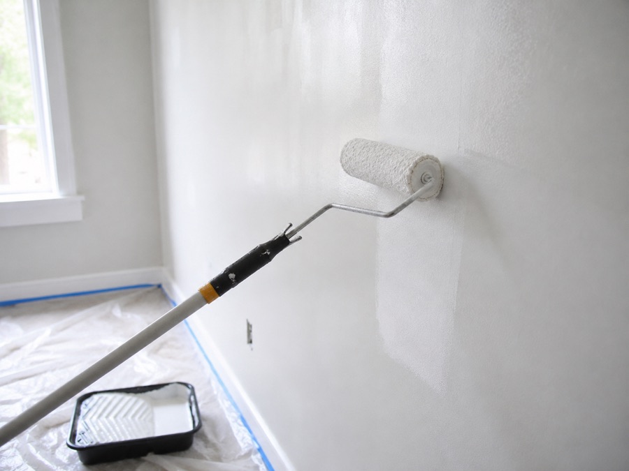 Painter rolling fresh white paint on an interior wall