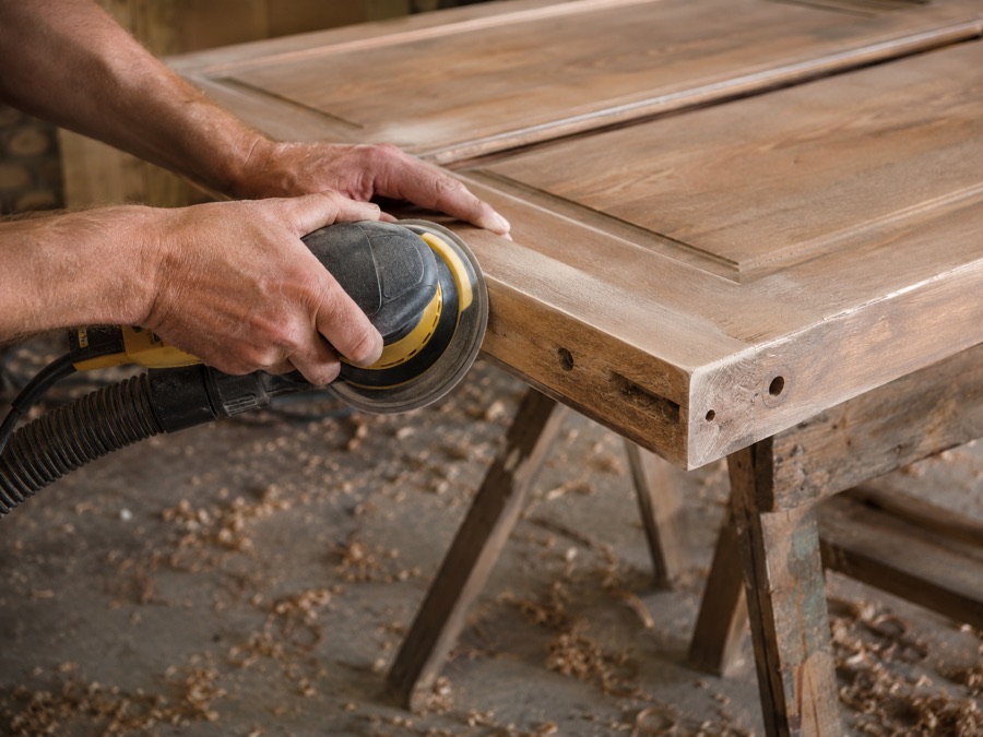 Carpenter sanding a wooden door edge