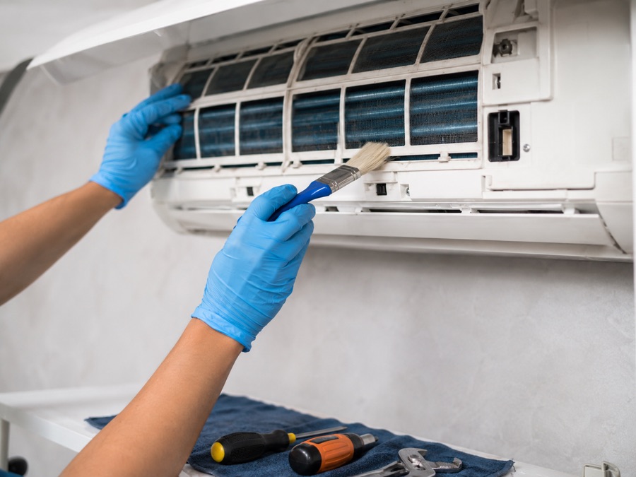 Technician cleaning an indoor AC unit filter